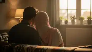 Couple musulman assis côte à côte devant une fenêtre au lever du jour, vu de dos